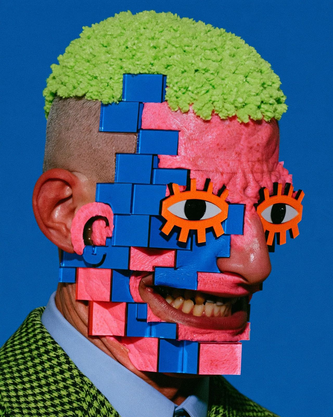 Photo of a person in a green houndstooth jacket with fuzzy lime hair, a face covered in pink and blue blocks, and orange cutout eyes, on blue.